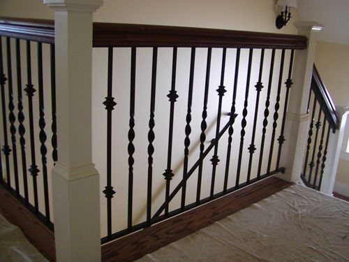 A staircase with a wrought iron railing and a wooden handrail