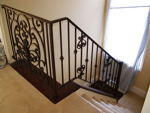A staircase with a wrought iron railing and a window