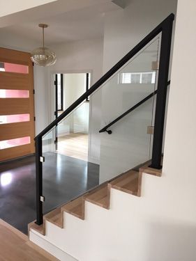 A staircase with a glass railing and a black railing in a house.