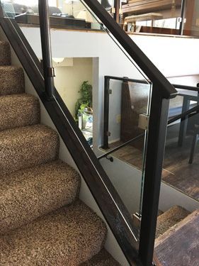 A staircase with a glass railing and a carpeted staircase.