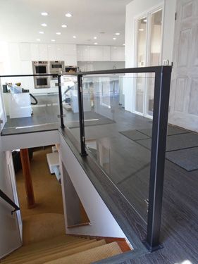 A staircase with a glass railing leading up to the second floor of a house.