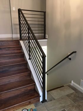 A wooden staircase with a metal railing in a house.