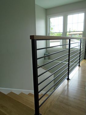 A staircase with a black railing and a wooden handrail.