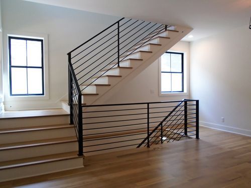 A staircase with a black railing in an empty room