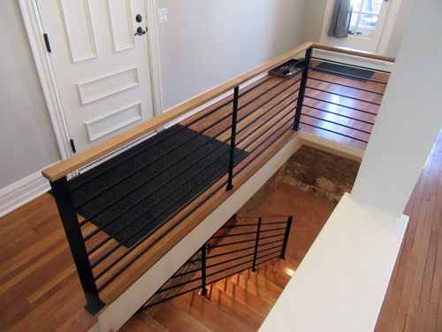 A staircase with a black railing and wooden handrail
