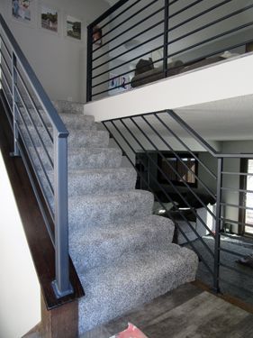 A set of stairs leading up to a loft with a metal railing