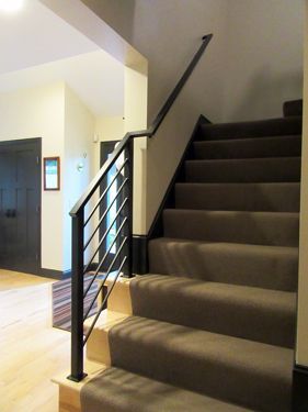 A staircase with a carpeted staircase and a black railing