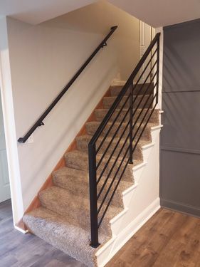 A staircase with a black railing and carpeted steps in a house.