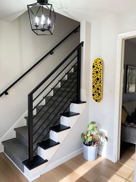 A staircase with a black railing and a yellow skateboard on the wall.