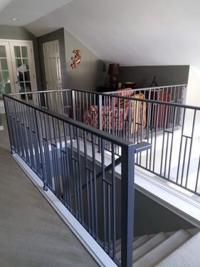 A staircase with a black railing and a living room in the background