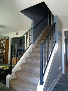 A set of stairs with a black railing in a living room