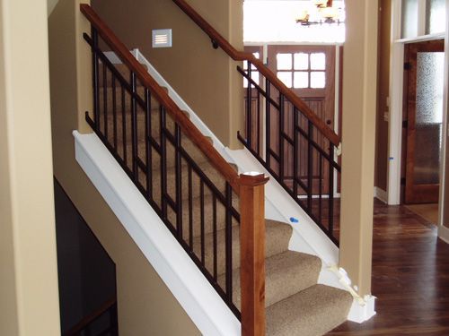A staircase with a metal railing and wooden handrails