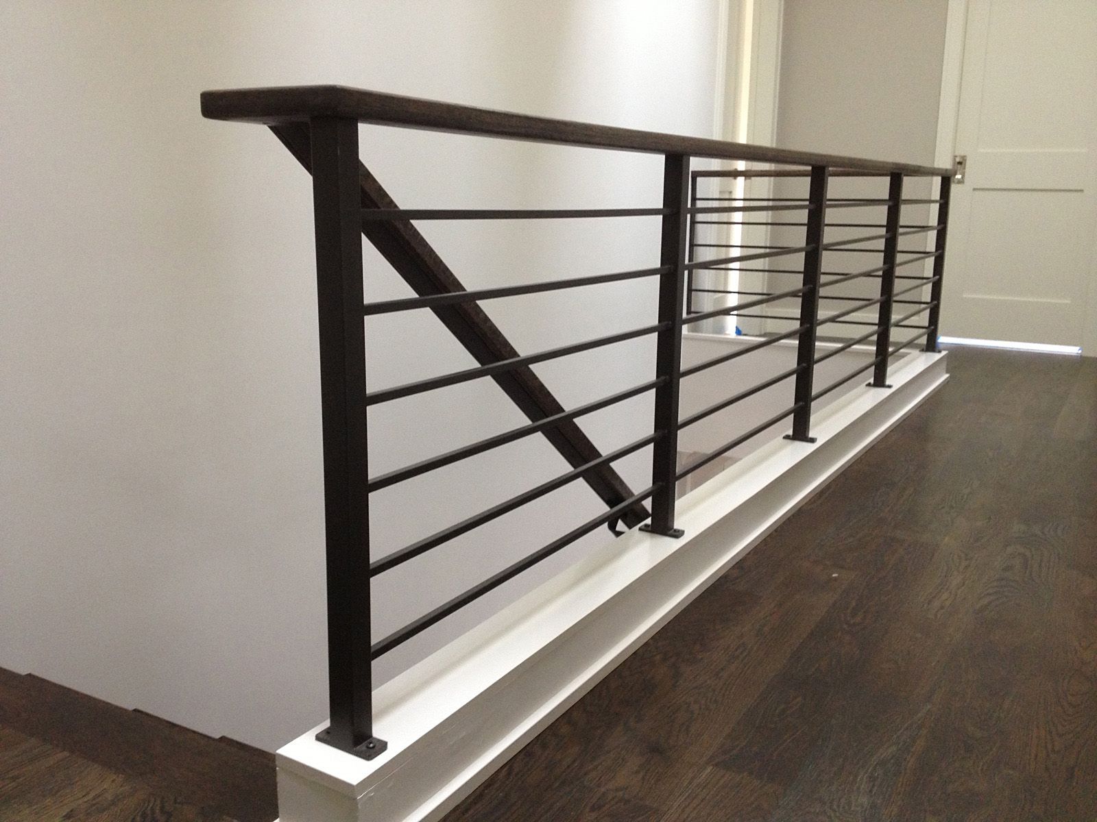 A staircase with a black railing and a wooden handrail