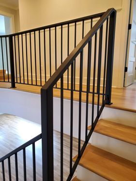A staircase with a black railing and wooden steps in a house.