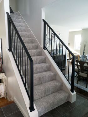 A staircase with a black railing and carpeted steps in a living room.