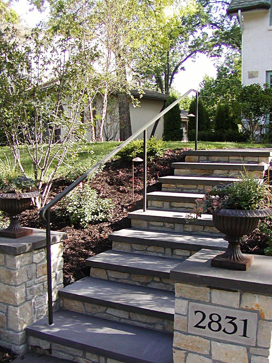 A set of stairs with a metal railing going up a hill.