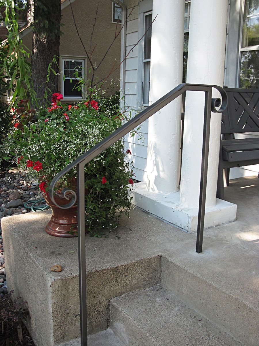 A wrought iron railing on the cement steps of a house