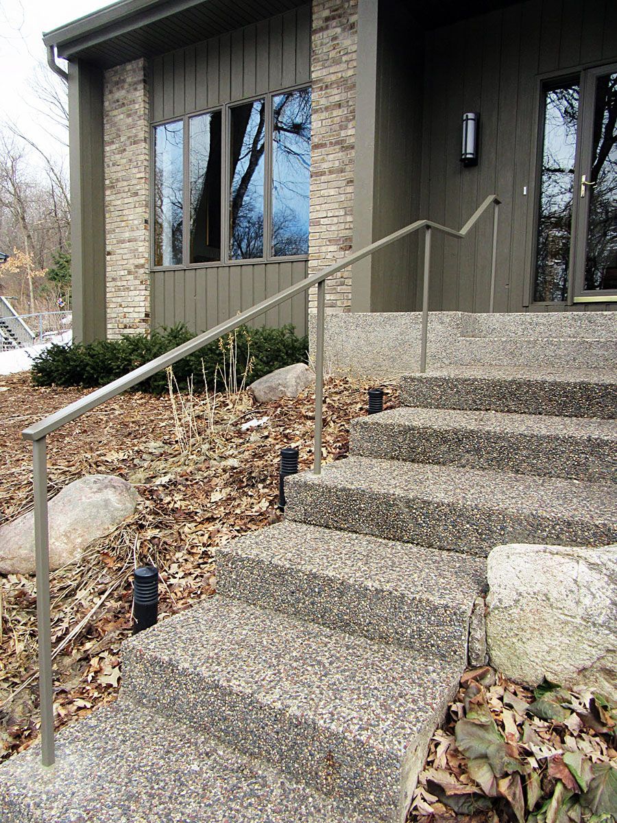 Concrete steps leading up to a house with a handrail. The steps have a speckled texture.