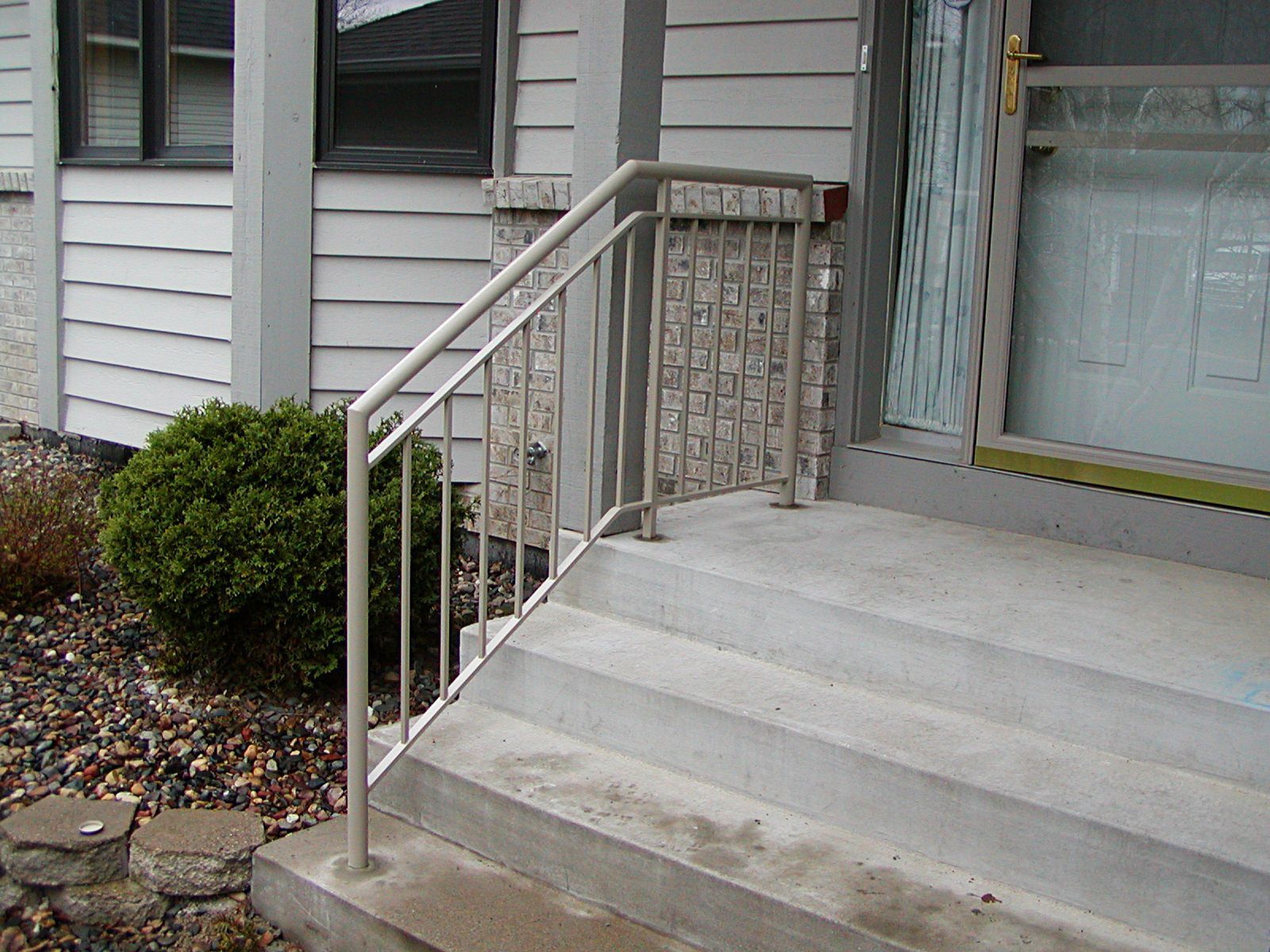 Concrete steps with metal handrail leading to a front door.