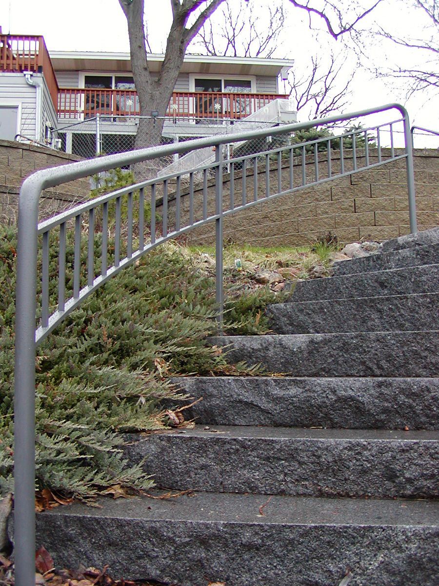 Granite steps with a metal railing leading up to a house with a deck.