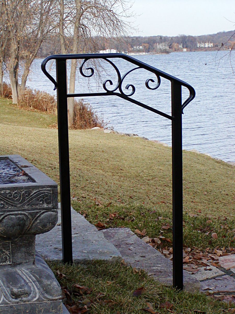 Black wrought-iron railing with scroll details on a lakefront.
