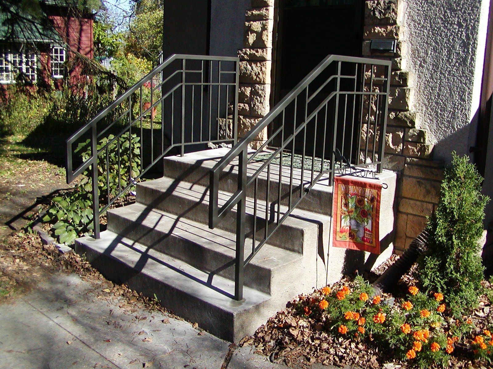 Concrete steps with black metal handrails leading to a stone building entrance.