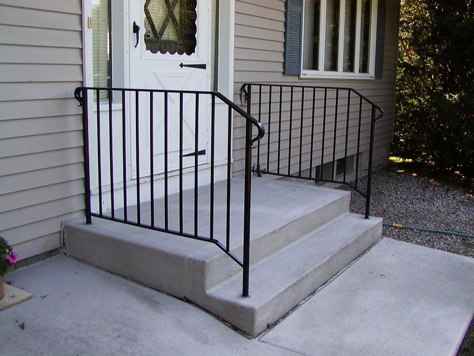 Concrete steps leading to a front door, with black metal handrails.
