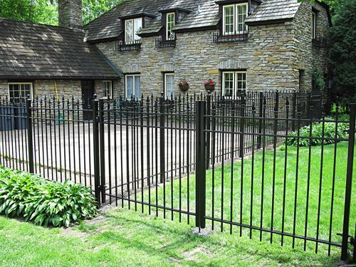 A stone house with a wrought iron fence in front of it.