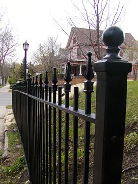 A black fence with a house in the background