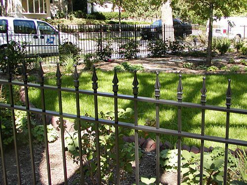 A wrought iron fence surrounds a lush green yard