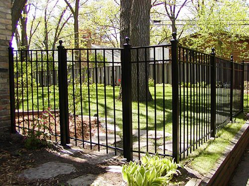 A black wrought iron fence surrounds a lush green yard.