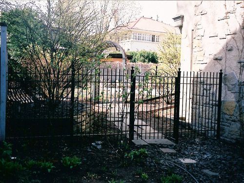 A wrought iron fence surrounds a stone wall
