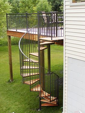 A spiral staircase leading up to a deck in the backyard of a house.