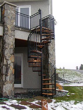 A spiral staircase is attached to the side of a house.
