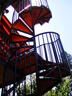 A red spiral staircase with a black railing