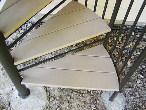 A spiral staircase with wooden steps and a metal railing.