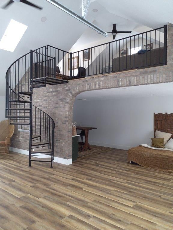 A living room with a spiral staircase leading to the second floor