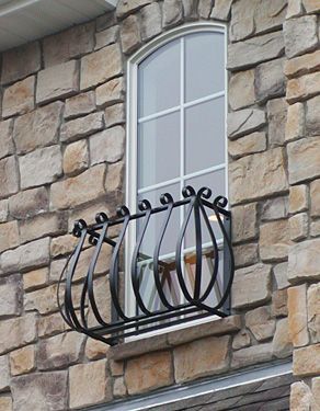 A window with a wrought iron balcony on a brick building