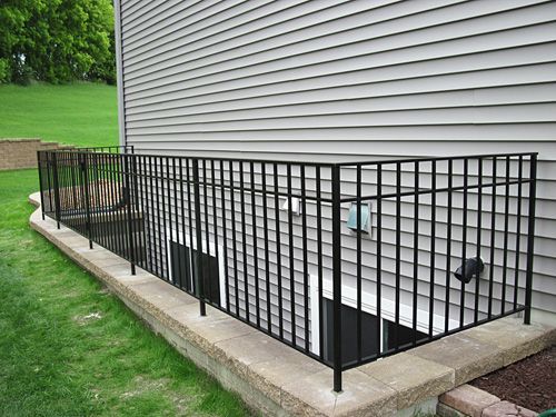 There is a fence around the basement of a house.