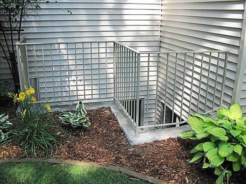 A white house with a staircase leading up to a basement window.