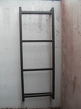 A metal ladder is hanging on a white wall.
