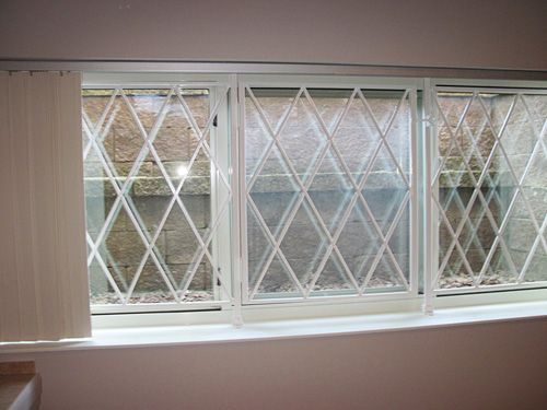 A window with a wrought iron grille on it in a room.