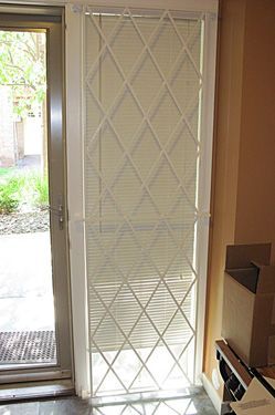 A white door with a diamond pattern on it is sitting in a room next to a door.
