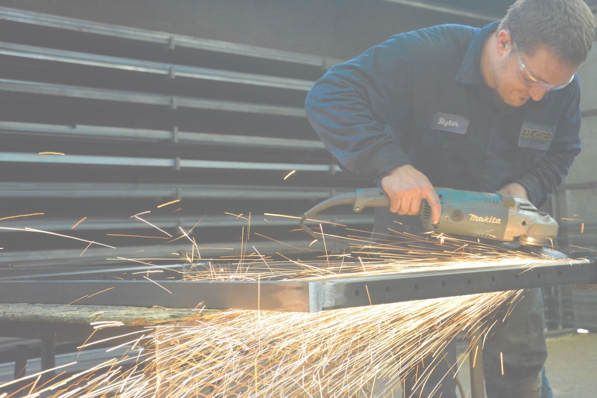 A man is using a grinder to cut a piece of metal