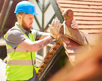 a man wearing a hard hat and safety vest is working on a roof .