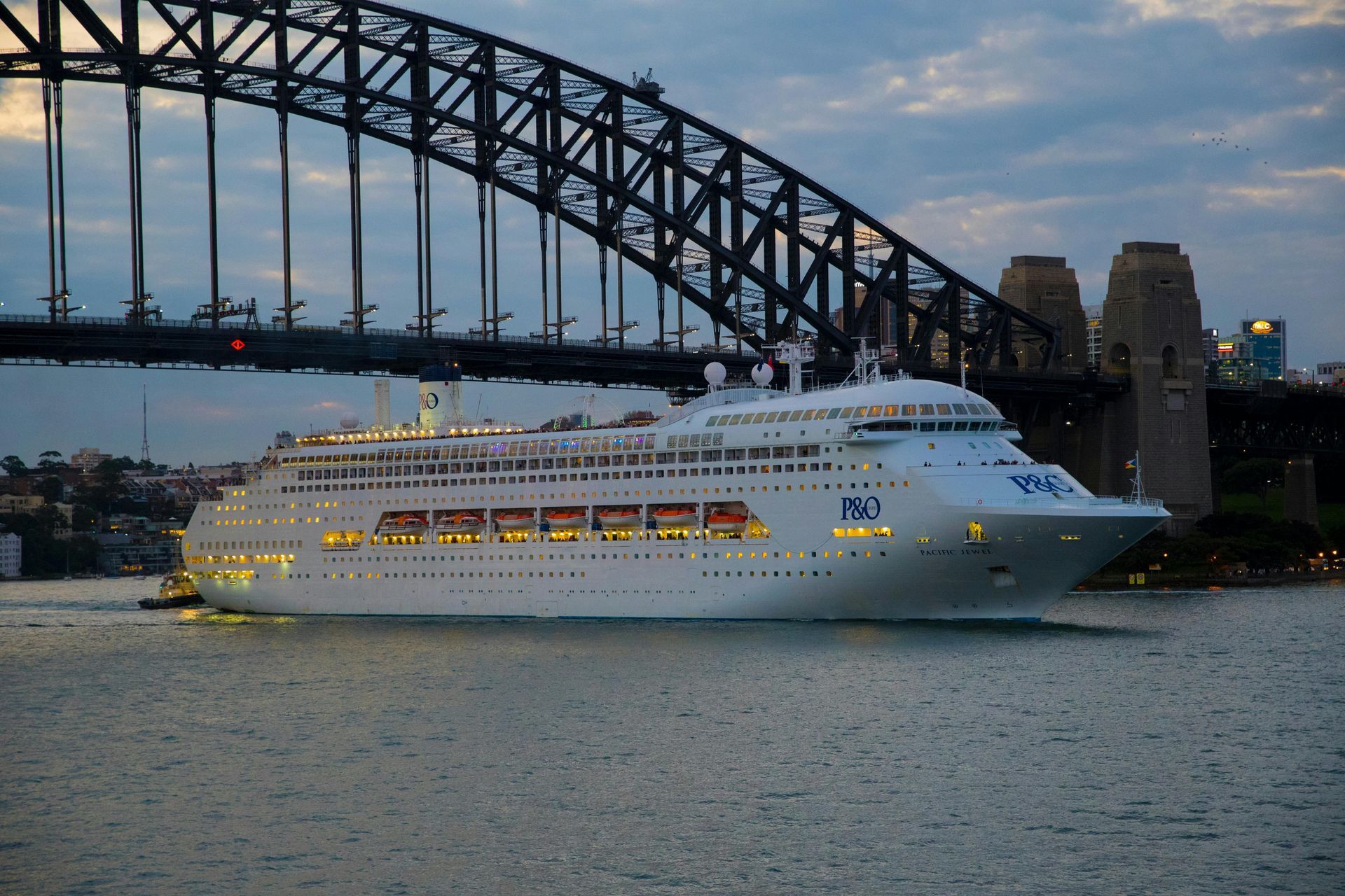 Cruise ship under Sydney Harbour Bridge at dusk.