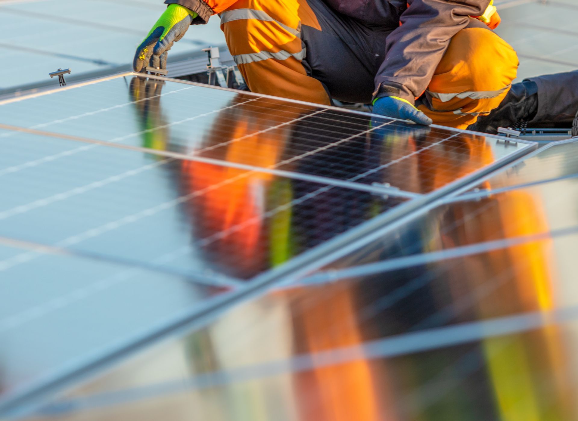 Operai con dispositivi di sicurezza che installano pannelli solari su un tetto.
