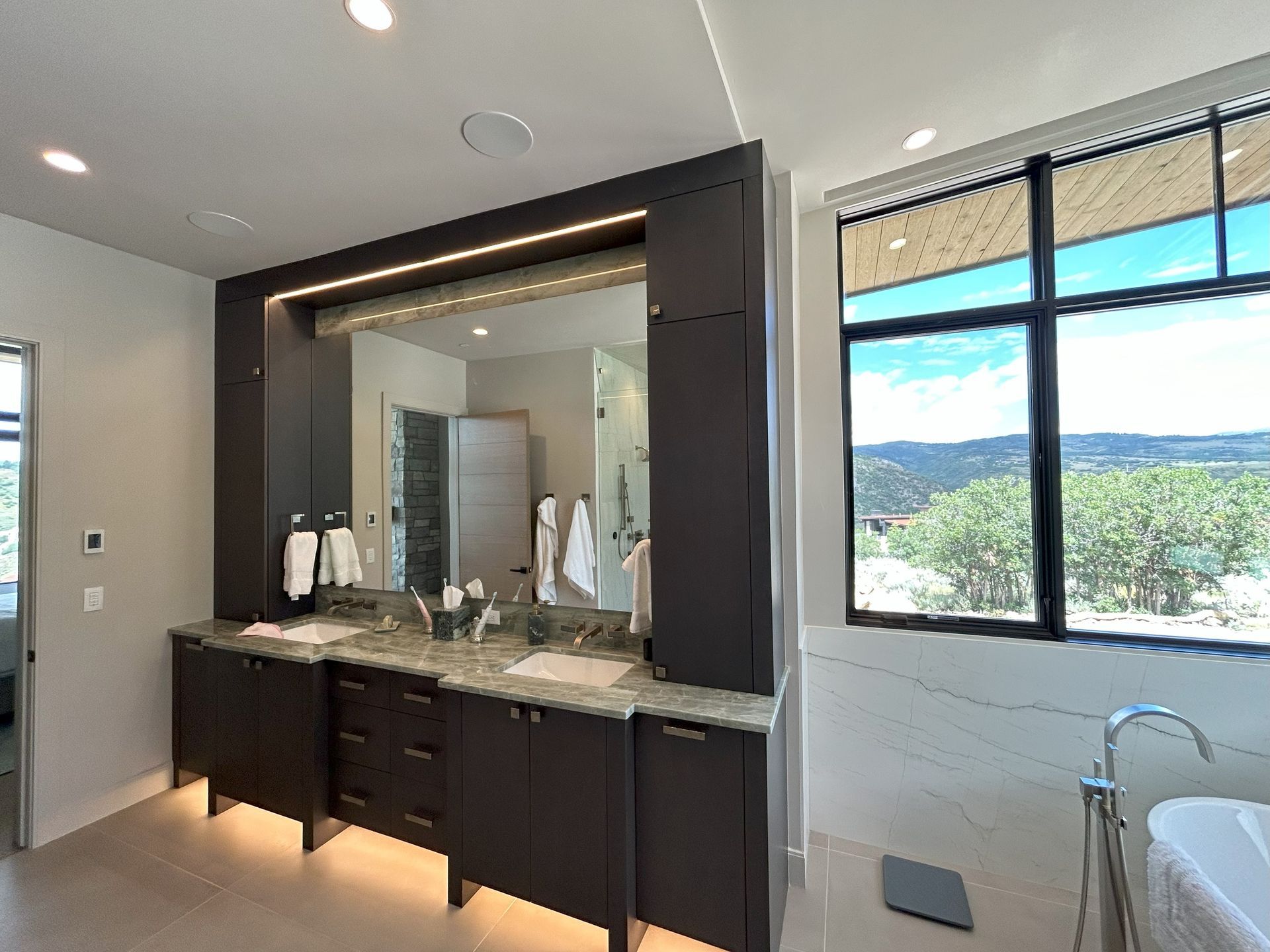 A bathroom with two sinks , a tub and a large mirror.