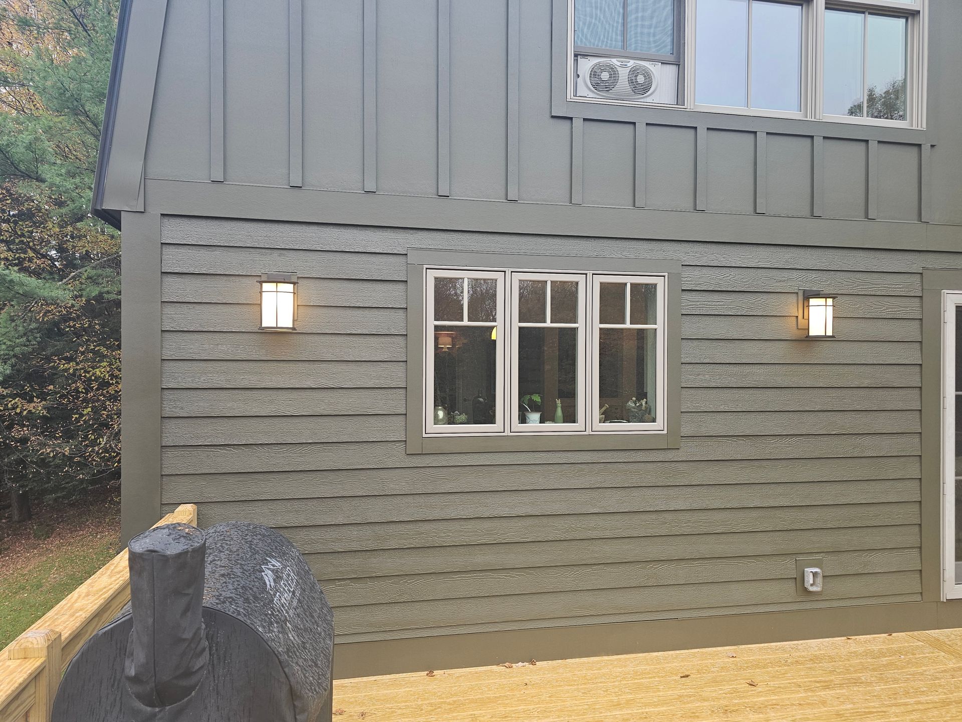 Exterior view of a building with gray siding, windows, and two wall-mounted lights.