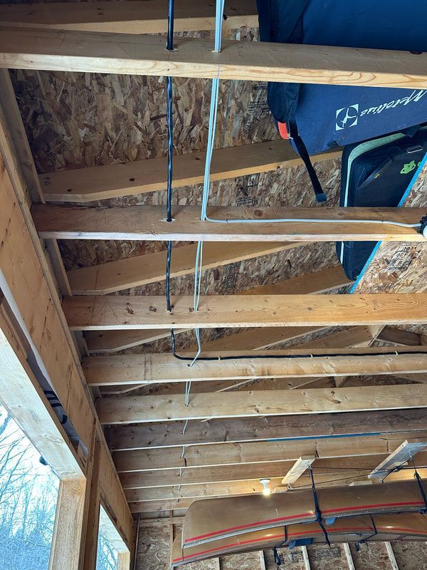Wooden rafters and plywood ceiling of a shed, with equipment hanging.